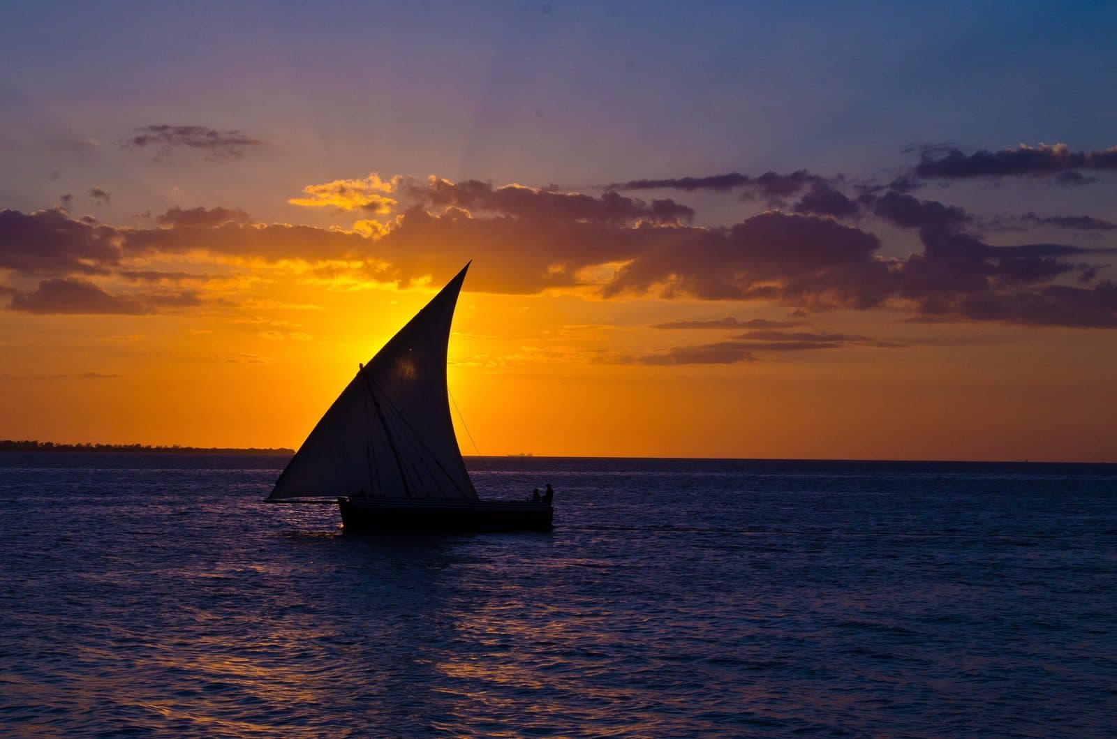 A dhow silhouetted against a golden sunset off the Zanzibar coast