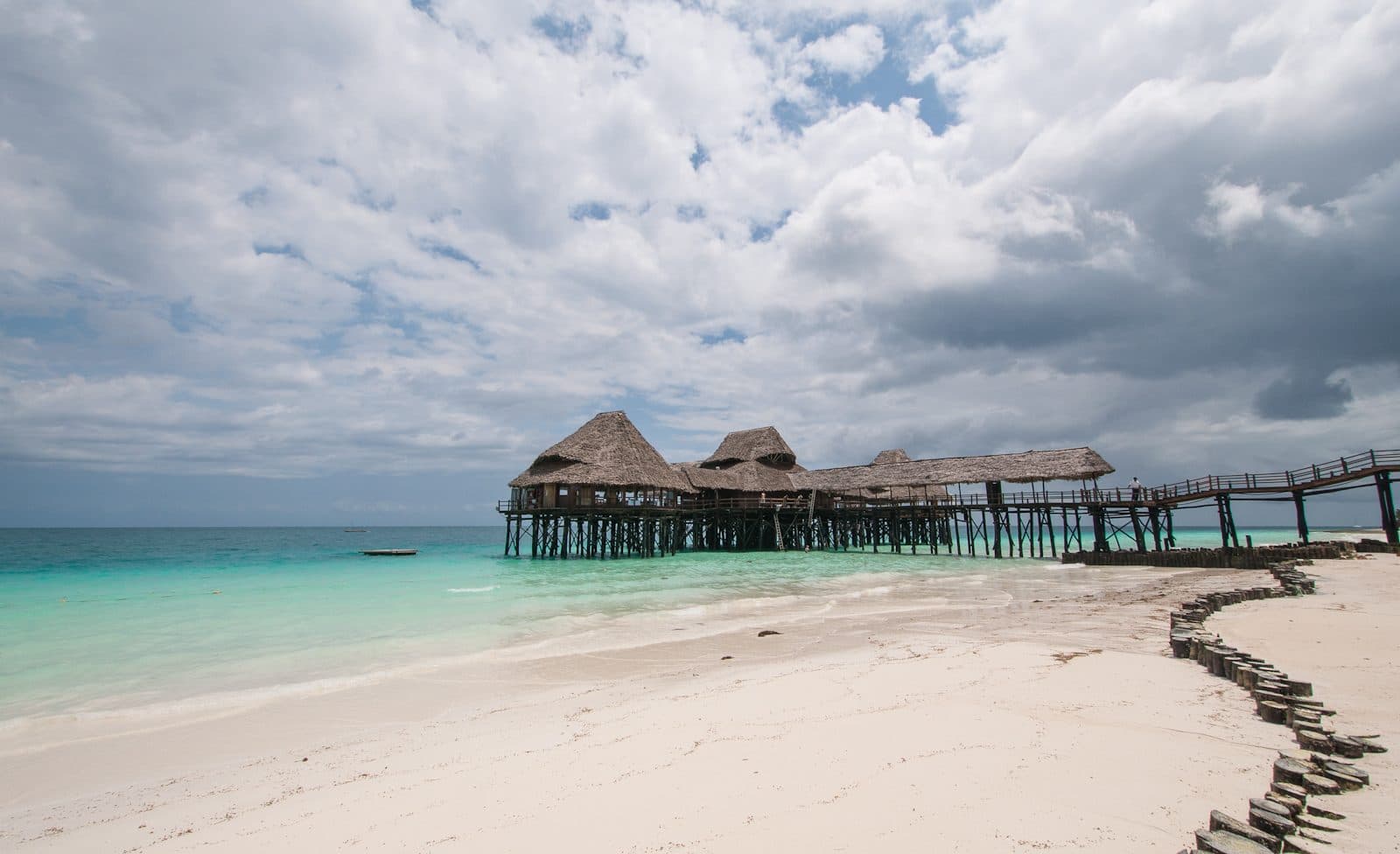 A thatched pier restaurant standing on stilts over turquoise water at Kendwa beach