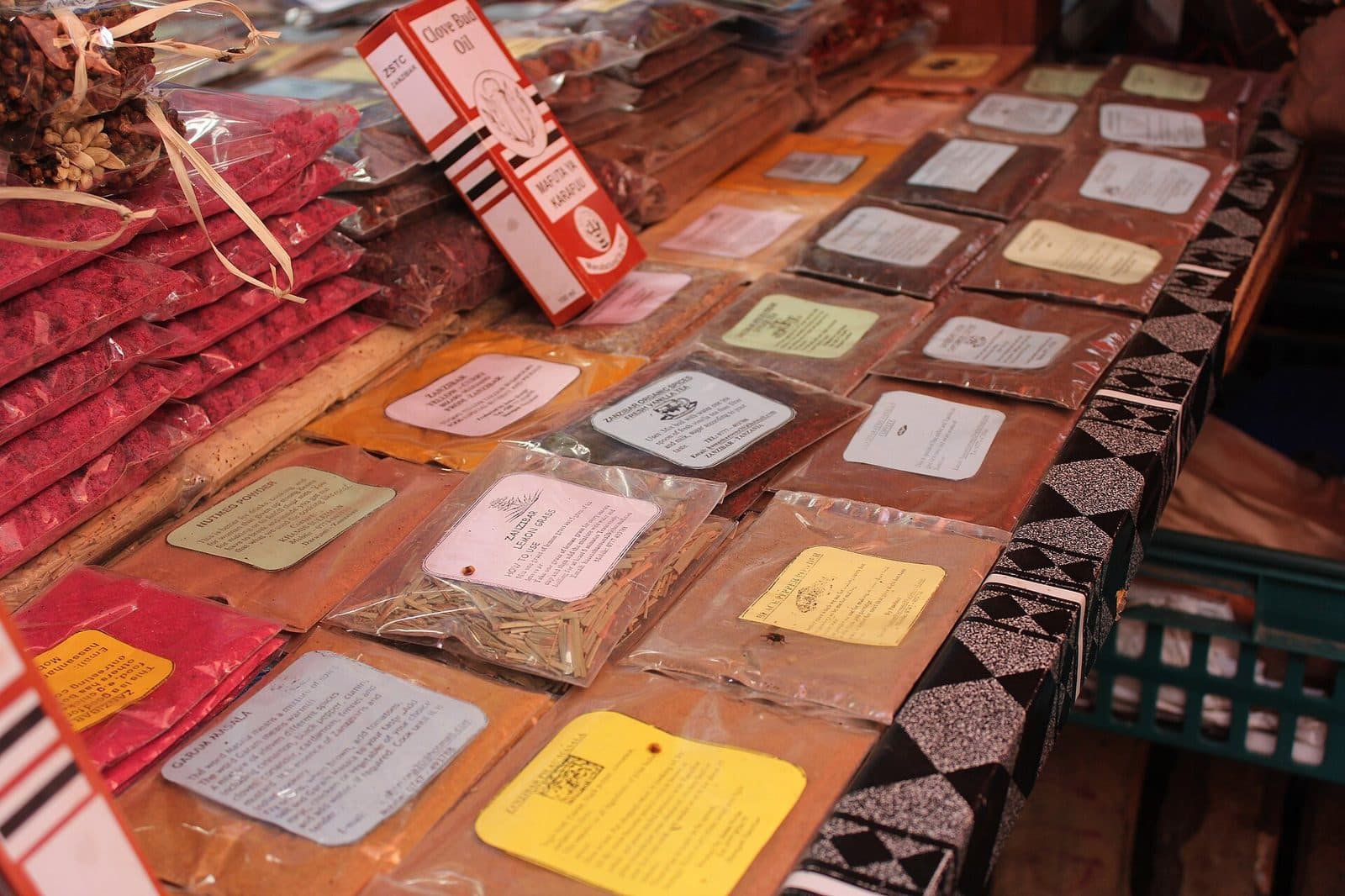 Ein Marktstand in Stone Town mit verpackten Gewürzen, Masala-Mischungen und Nelkenknospenöl auf einem Holztisch